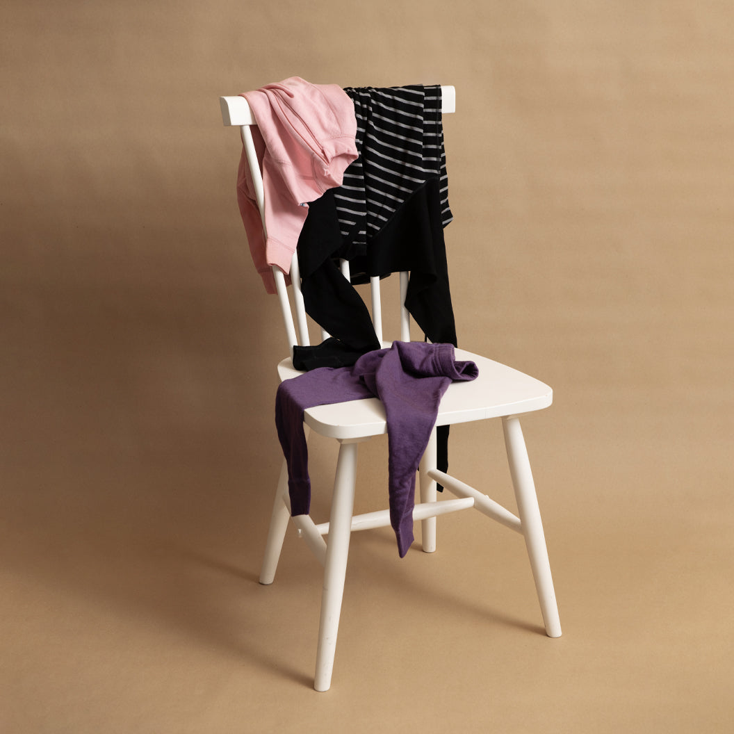 Polarn O. Pyret children’s clothing draped on a white wooden chair 